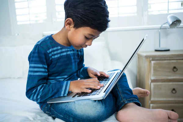 Menino usando laptop enquanto relaxa na cama — Fotografia de Stock