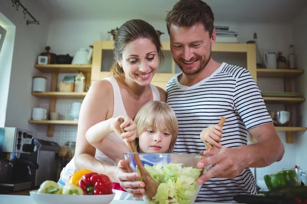 Родители смотрят, как их дочь смешивает салат — стоковое фото