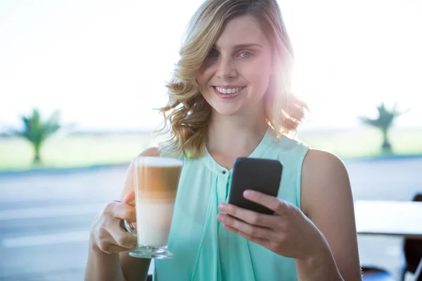 Женщина держит кофе и с помощью телефона — стоковое фото