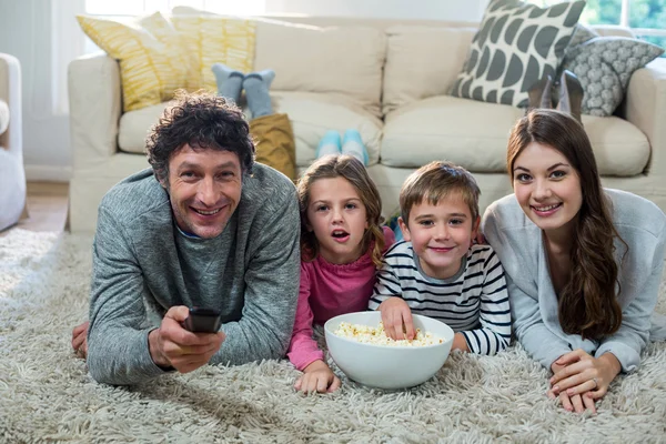 Família assistindo televisão enquanto deitado no chão — Fotografia de Stock