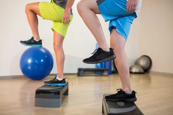 Uomini che fanno passo esercizio aerobico su stepper — Foto Stock