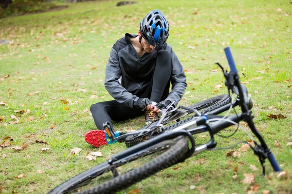 公園で、靴ひもを結ぶ男性サイクリスト — ストック写真