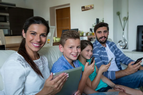 Dizüstü bilgisayar ve telefon oturma odasında kullanarak aile — Stok fotoğraf