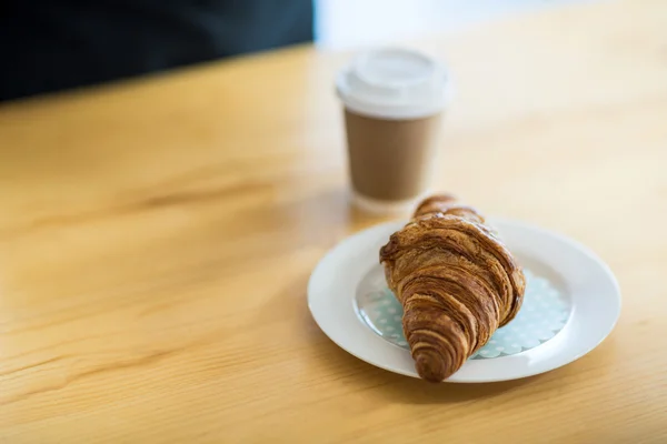 Croissant on plate in cafeteria — Stock Photo, Image