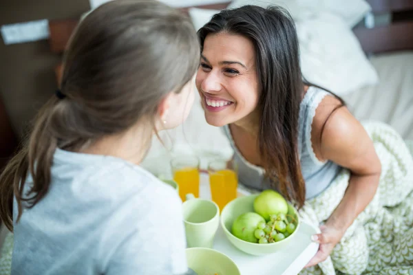 Mother and daughter having breakfast on bed — Stockfoto