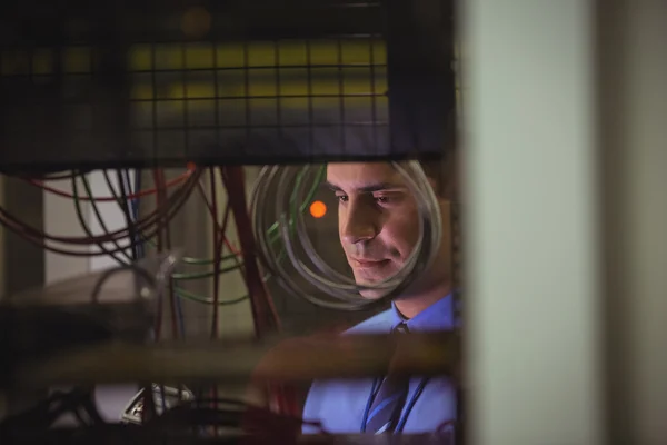 Technician checking cables in rack mounted server — Stockfoto