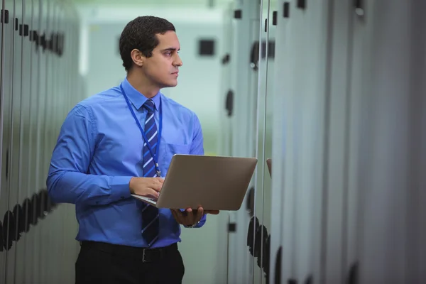 Technician using laptop while analyzing server — Stock Photo, Image