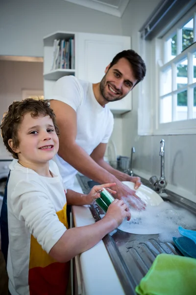 Hijo ayudando a padre en los utensilios de lavado —  Fotos de Stock