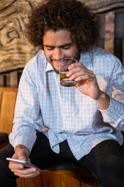 Hombre usando el teléfono mientras toma whisky — Foto de Stock