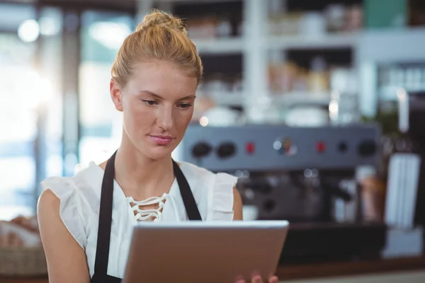 Официантка, стоящая за прилавком с помощью планшета — стоковое фото