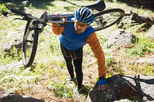 Motociclista de montanha masculino transportando bicicleta — Fotografia de Stock