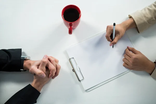 Zakenvrouw schrijven op Klembord met koffie op Bureau — Stockfoto