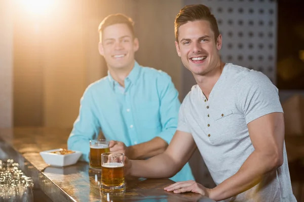 Amigos tomando cerveja no balcão do bar — Fotografia de Stock
