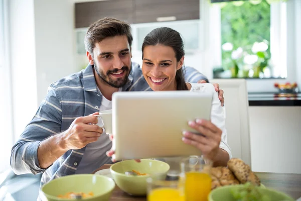 Пара, использующая цифровой планшет во время завтрака — стоковое фото