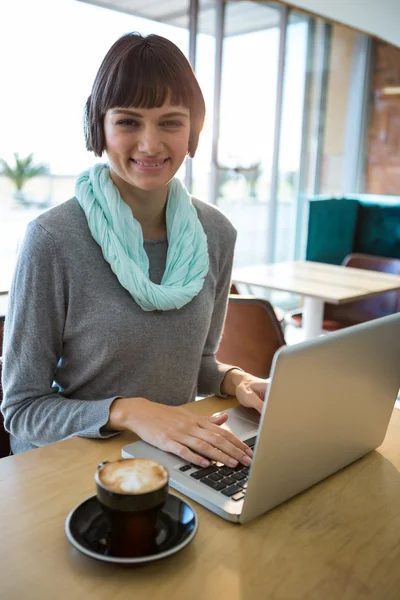 Donna che utilizza il computer portatile mentre prende il caffè — Foto Stock