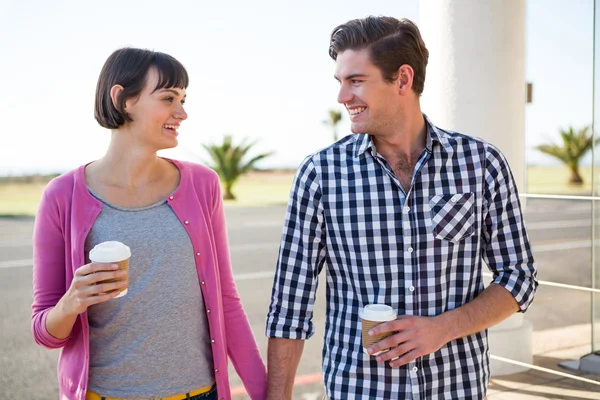Couple with coffee cups walking together — Stock Photo, Image