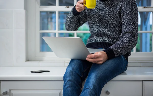 Uomo che utilizza il computer portatile mentre prende il caffè — Foto Stock