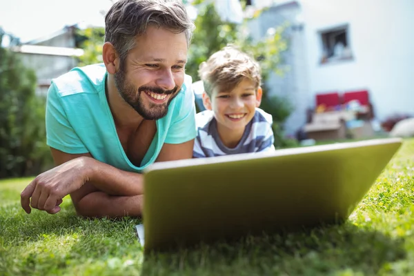 Father and son using laptop in garden — Stock Photo, Image