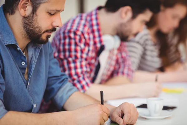 Businessman with coworkers writing on documents — Stock Photo, Image