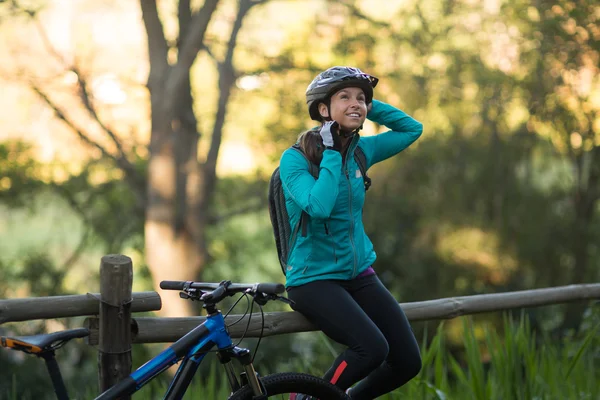女骑自行车的人坐在栅栏上 — 图库照片