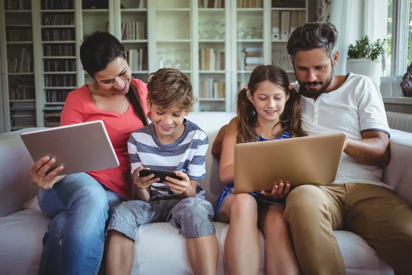 Famille utilisant un ordinateur portable, téléphone et tablette — Photo