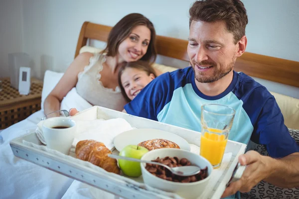 Father holding tray with breakfast on bed — Stock Photo, Image