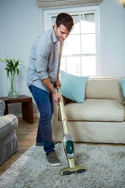 Man cleaning carpet with a vacuum cleaner — Stock Photo, Image