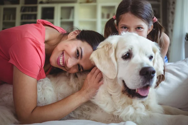 Mother and daughter sitting with pet dog in living room — Stock Photo, Image