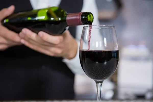 Barman nalévá červené víno na sklo — Stock fotografie