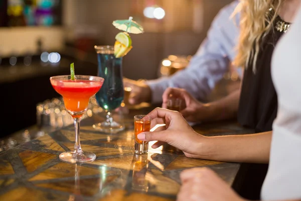 Friends holding a glass of tequila shot in bar — Stock Photo, Image