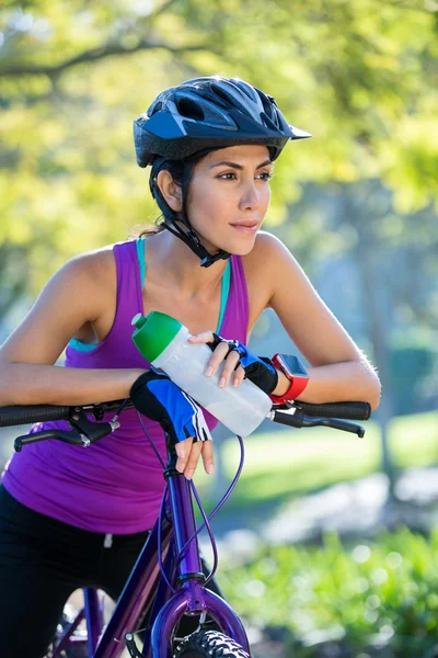 Vrouwelijke atletische leunend op de fiets op platteland — Stockfoto