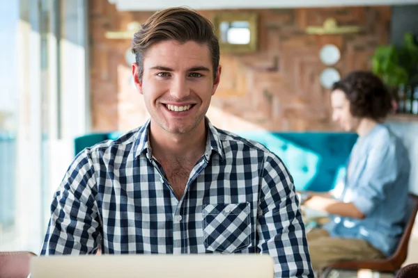Hombre sonriente sentado en la cafetería — Foto de Stock