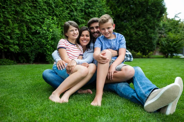 Familjen sitter på gräset i parken — Stockfoto