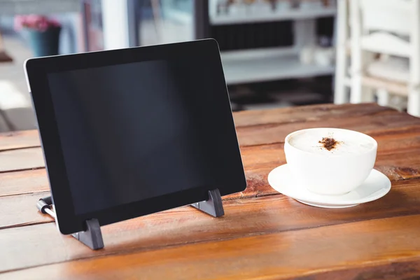 Coffee cup and tablet on a table — Stock Photo, Image