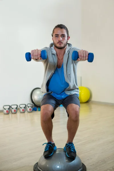 Hombre haciendo ejercicio con mancuernas en bosuball — Foto de Stock