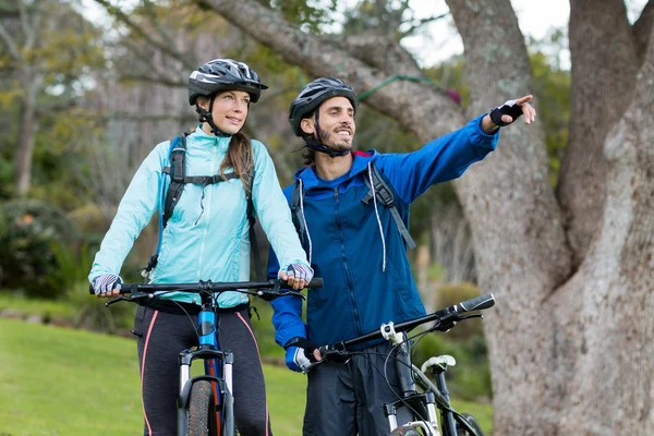 Байкерская пара с горным велосипедом, указывая на расстоянии — стоковое фото