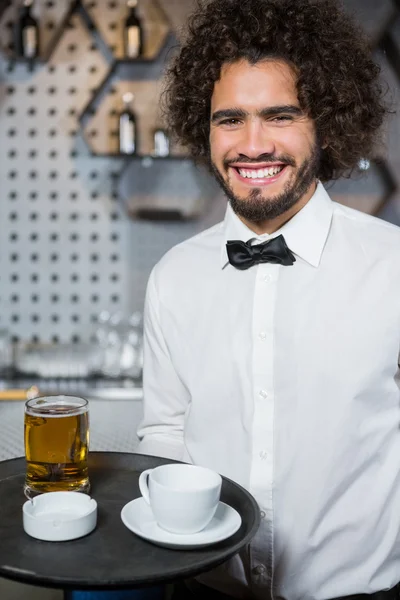 Servitören holding bricka av öl glas och tekopp — Stockfoto