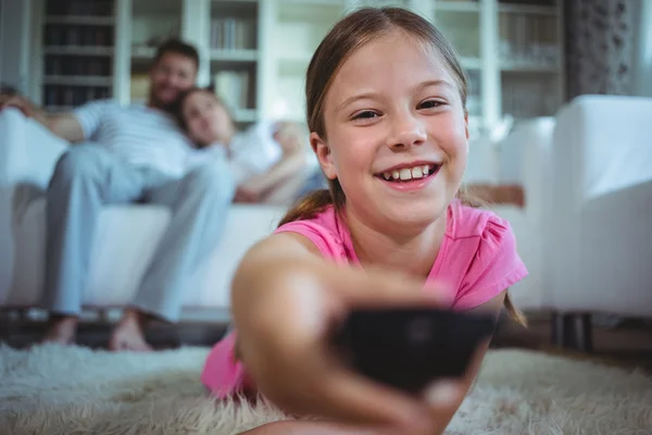 Girl lying on rug and changing channels — Φωτογραφία Αρχείου