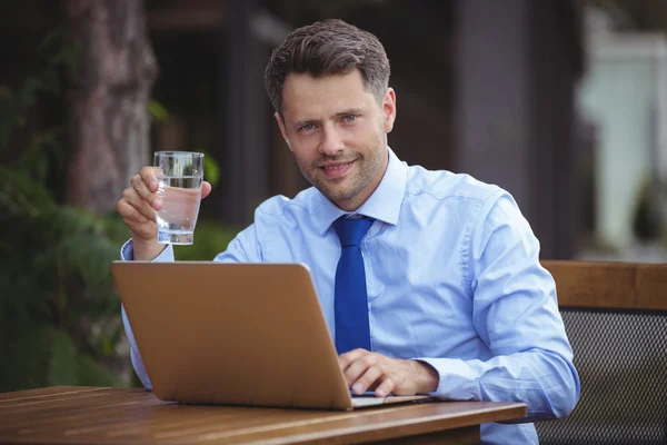 Empresário tendo bebida ao usar laptop — Fotografia de Stock