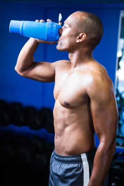 Shirtless man drinking water in gym — Stock Photo, Image