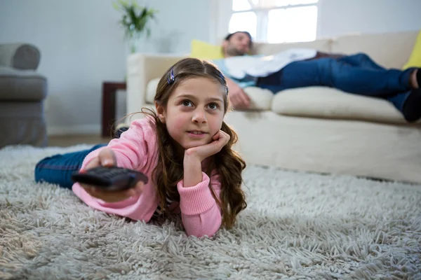 Menina assistindo tv deitado no tapete — Fotografia de Stock