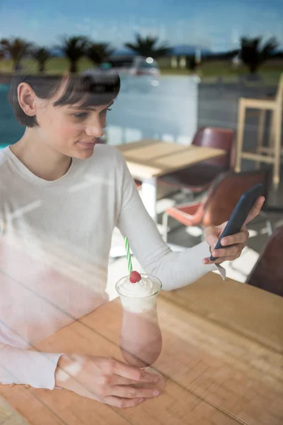 Mujer usando el teléfono mientras toma batido — Foto de Stock