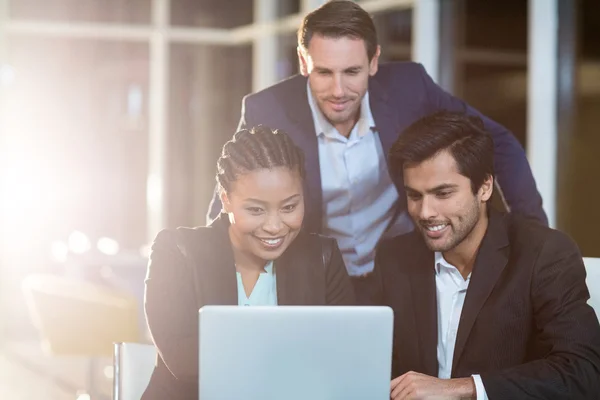 Empresária discutindo com colegas sobre laptop — Fotografia de Stock