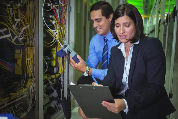 Technicians analyzing rack mounted server — ストック写真