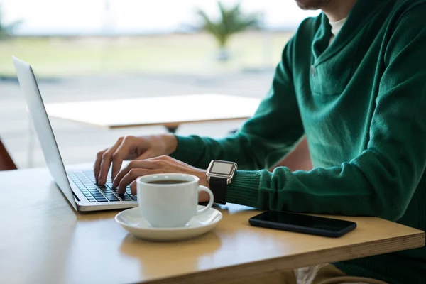 Hombre usando el ordenador portátil con taza de café y teléfono —  Fotos de Stock