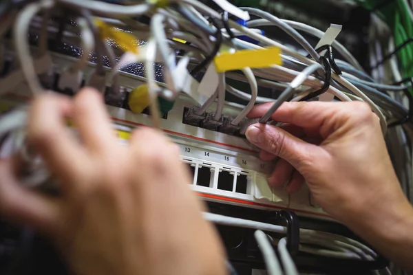 Technician plugging patch cable in rack mounted server — Stock fotografie