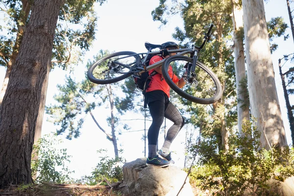 Αρσενικό βουνό ποδηλάτης που μεταφέρουν το ποδήλατο στο δάσος — Φωτογραφία Αρχείου