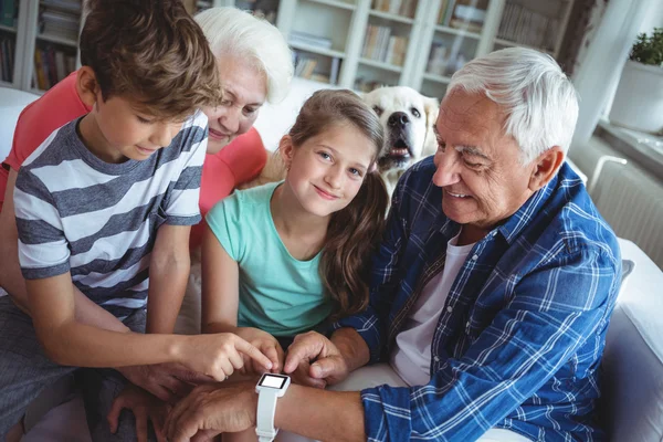 Far-och morföräldrar och barnbarn tittar på smartwatch — Stockfoto