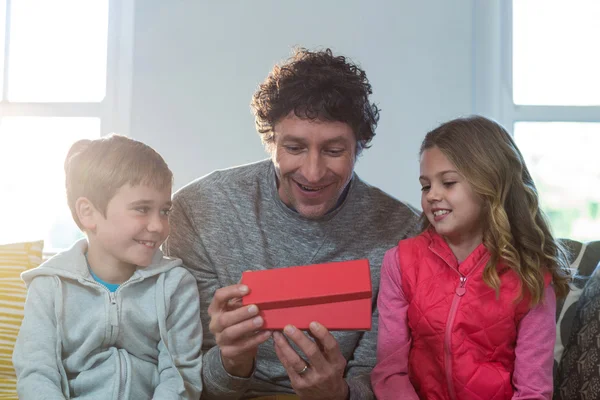 Father opening gift box with children