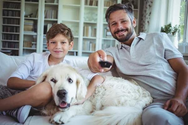 Pai e filho com cão de estimação assistindo televisão — Fotografia de Stock